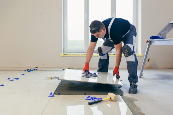 A male construction worker installs a large ceramic tile A male construction worker installs a large ceramic tile